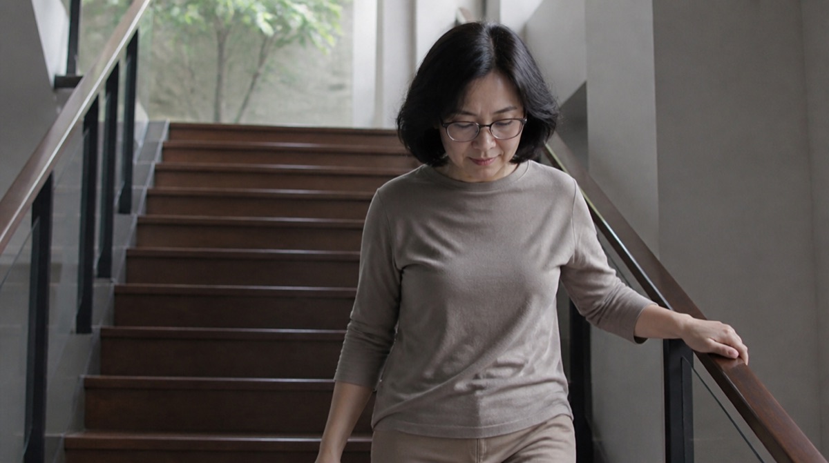 새 안경을 쓰고 턱을 살짝 당긴 채 조심스럽게 계단을 내려가는 50대 여성